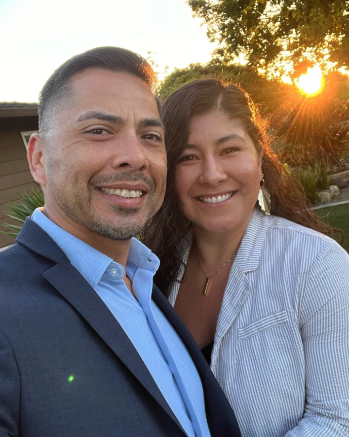 Eddie Guajardo and his wife, Marty, smiling together outdoors at sunset.