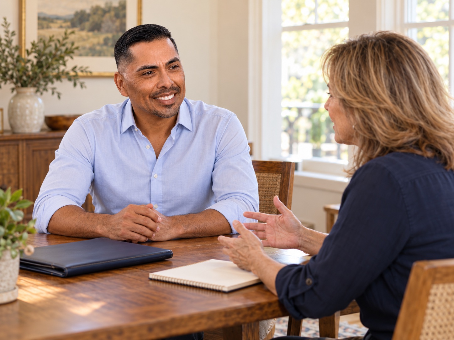Eddie Guajardo in a light blue business casual shirt listening to a homeowner during a private consultation.